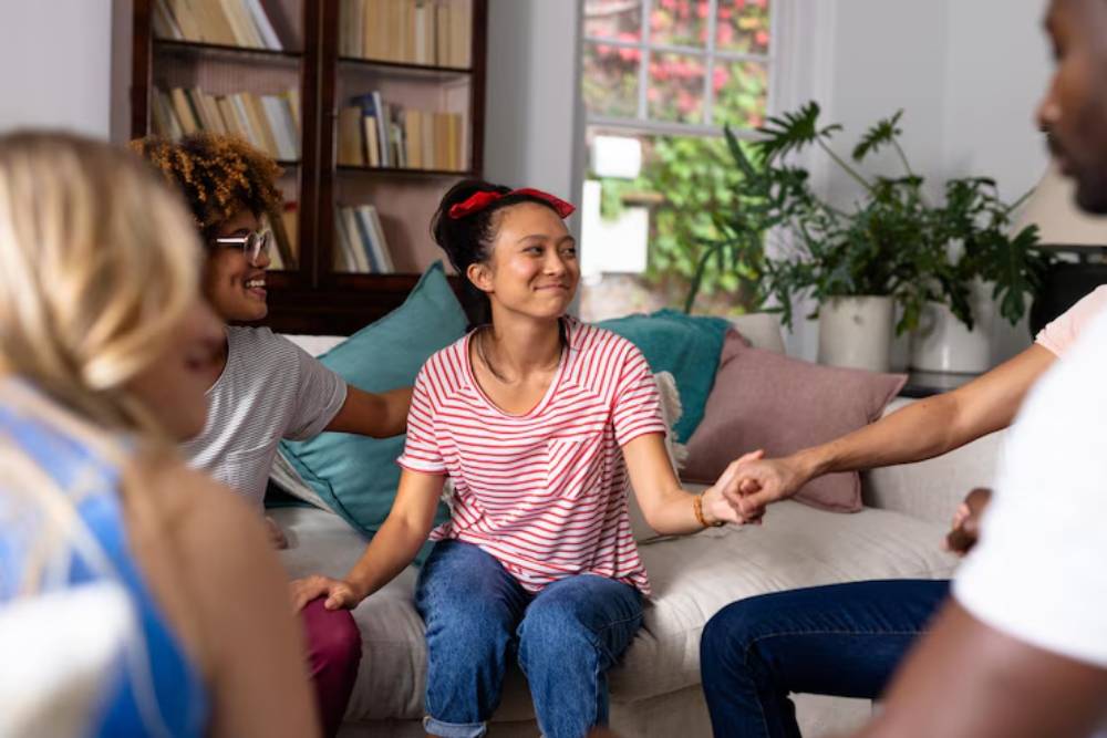 Clients in Outpatient Rehab in Columbus OH participate in a supportive group therapy session, holding hands and fostering emotional connection.
