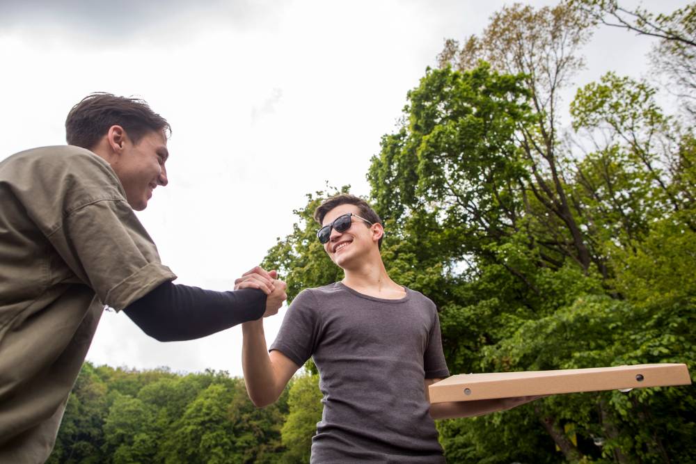 Two young men smiling and shaking hands outdoors, symbolizing recovery and support through Meth Addiction Treatment in Columbus OH.